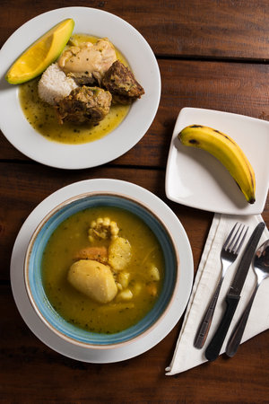 Traditional Colombian dish of soup of three different types of meat with potatoes and cooked corn accompanied by bananasの写真素材