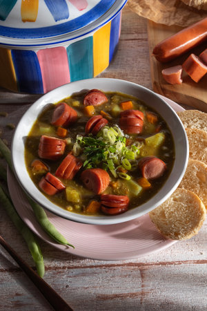A close-up of a ladleful of sausage and potato soup, showing the rich, creamy texture and the tender pieces of sausage and potato.の写真素材