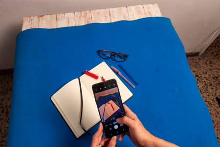 Overhead shot of hands, phone, notebook, and thoughts on a vivid blue surface. Conceptual image for content creation, note-taking, and technology integration in daily life.の写真素材