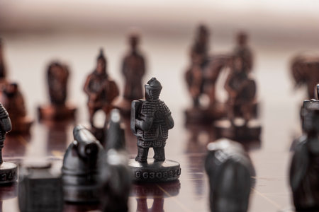 A high-contrast studio photograph of the complete physical Chinese Chess set. The brass and copper pieces evoke themes of competition, heritage, ancient warfare, and critical decision-making processes.の写真素材