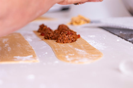 Generational Recipes: Hand-Making Delicious Ravioli, Focused shot on adult hands as they prepare fresh pasta, embodying dedication to healthy eating and the simple, satisfying process of making food for loved ones.の写真素材