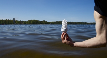 Strong arm holding energy saving bulb in beautiful atmosphere
