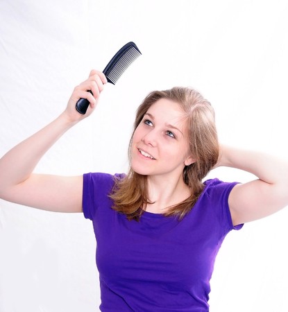 Studio Shot of a beautiful girl in a blue t-shirt dressing her hair, isolated on white background