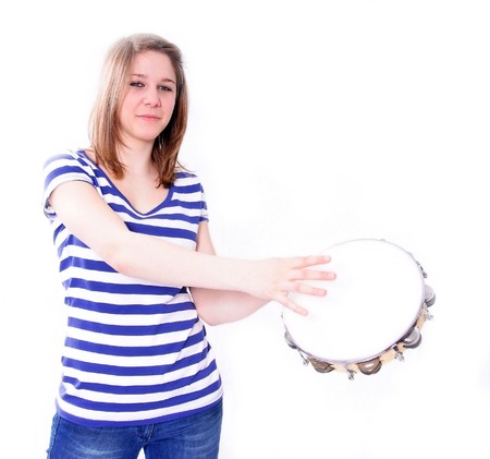 Studio Shot of a beautiful young woman in blue jeans and blue-white t-shirt playing percussion, isolated on white backgroundの写真素材