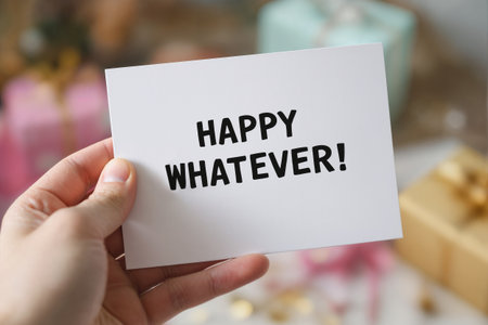 A hand holding a funny, sarcastic greeting card with the text Happy Whatever. Closeup, shallow depth of field.の素材