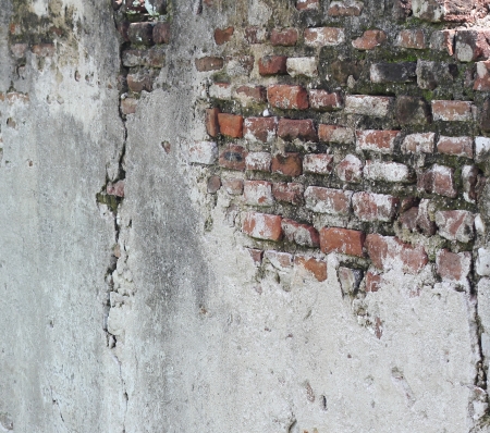 A section of an old and crumbling wall with underlying aged bricks exposedの写真素材