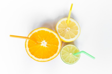 Citrus fruit with yellow orange and green straws on white background from aboveの写真素材