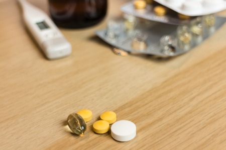 varied pills on wooden table with thermometer pills and syrup in the backgroundの写真素材