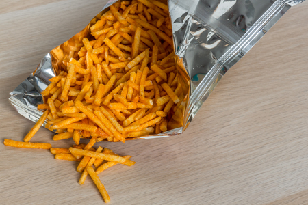 Opened pack of salty pepper stick snack on wooden tableの写真素材