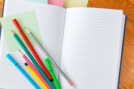 Colorful pencils and felt-tip pens on opened lined notebook.の写真素材