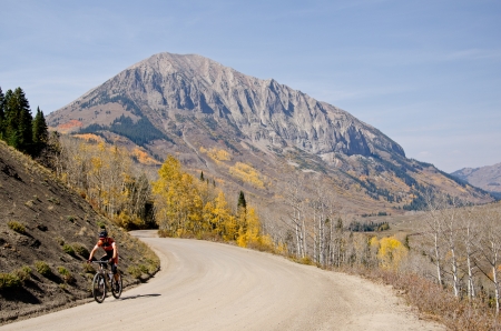 A mountian biker on picturesque Gothic Road in with fall colors and Gothic Mountain in the background のeditorial素材