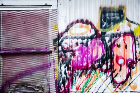 Colorful grafitti and paint and a window on an old warehouse in downtown Colorado Springs by the railroad tracks  のeditorial素材