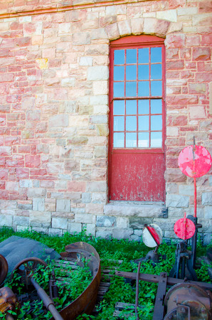 Red window and stone wall with vintage railroad signs and relics  at the Pikes Peak Trolley Museum in Colorado Springs, Colorado.の写真素材