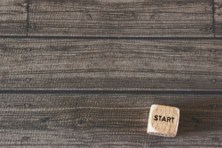 "Start" printed on wood dice against wood background with room for copyの写真素材