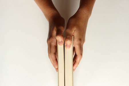 Young female hands hold a book starting to open. White copy space.の写真素材