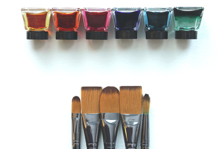 Rainbow colored liquid watercolors in a row with silver paintbrushes opposite. Copy space.の写真素材