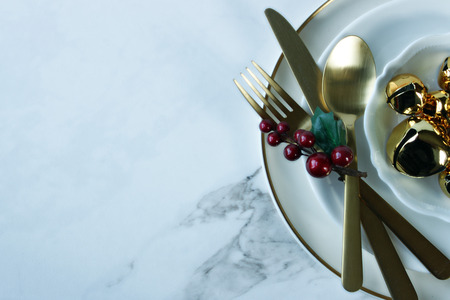 Modern styled table setting with gold accents and Christmas decor. Copy space.