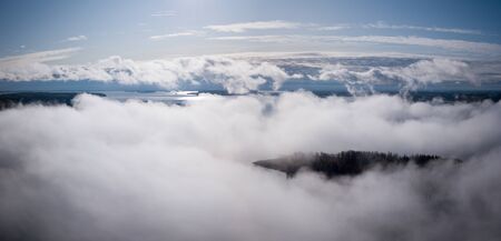 Aerial landscape view of morning fog hovering over sunny lake.