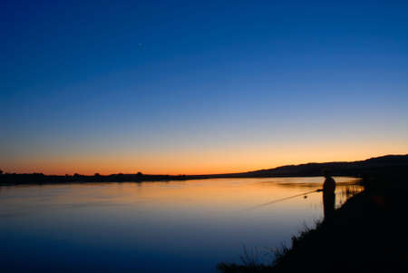 Fishing at sunset and first star in skyの写真素材
