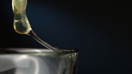 Human hand breaking an egg into a glass bowl. Close-up macro shot against a dark blue backgroundの写真素材