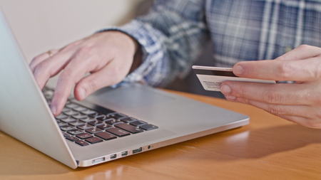 Close-up view of mans hands typing credit card number