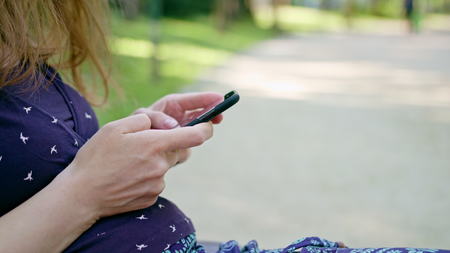 Woman taking a walk in the park using a cellphone. Dolly shot. Soft focus.の写真素材