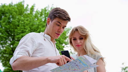A young blonde couple using a smapthone outdoors. Looking for directions. Soft focus. Medium shootの写真素材