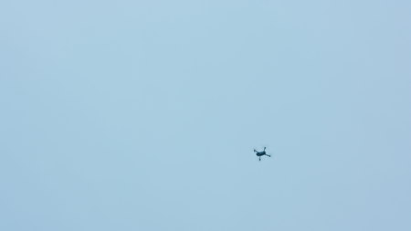 Flying drone with blue sky background, steady in air. Medium. Outdoors. Sunny. Stabilized. No peopleの写真素材