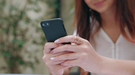 A beautiful girl using her mobile phone in the room. Closeup shot. Soft focus.の写真素材