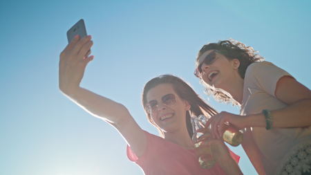 Two young ladies making a selfie on the beach. Medium shot. Soft Focus.の写真素材