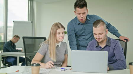 Creative business team meeting in modern start up office male team leader pointing at screen...