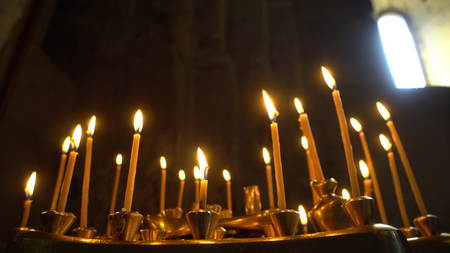 Taper candles burning in church. Close-up shot
