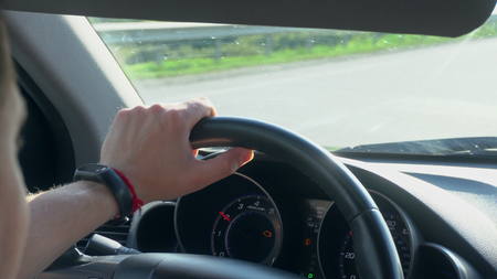 Inside a car. A mans hands on the steering wheel. Close-up shotの写真素材