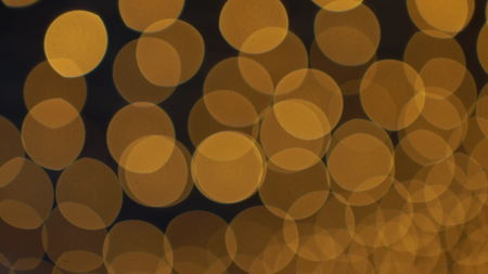 Golden bokeh lights blinking against a dark background.の写真素材