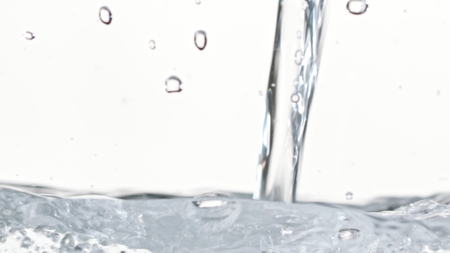 Macro footage of water pouring in a transparent container. White background. Close-up macro shot.の写真素材