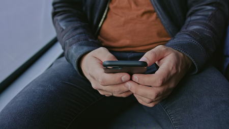 A young man using a smartphone on the bus. Close-up shot.の写真素材