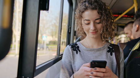 A young lady using a smartphone on the bus. Medium shot.