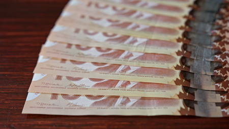 Lublin, Poland - September 2017: Fanned pile of Canadian hundred dollar banknotes on a table....