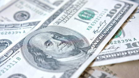 A pile of hundred dollar banknotes on a table. Close-up dolly shot