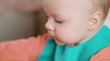 A baby girl eating puree at home. Close-up shot. Soft focus.の写真素材