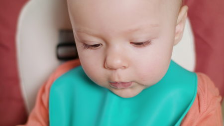 A baby girl eating puree at home. Close-up shot. Soft focus.の写真素材