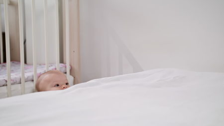 Babys standing near the bed at home and playing. Medium shot.の写真素材