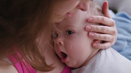 A young mother holding her baby daughter in her arms. Close-up shot