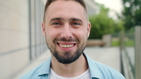 A happy smiling man with a beard in the city street. Close-up shot. Soft focusの写真素材