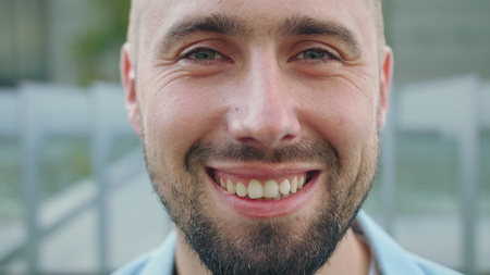 A happy smiling man with a beard in the city street. Close-up shot. Soft focusの写真素材