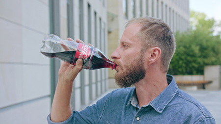 Chicago, USA - June 30 2018: A man with a beard sitting in front of a large building and drinking cola. Close-up shot. Soft focusのeditorial素材
