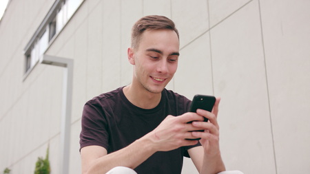 A young man using a phone in the city street. Close-up shot. Soft focus