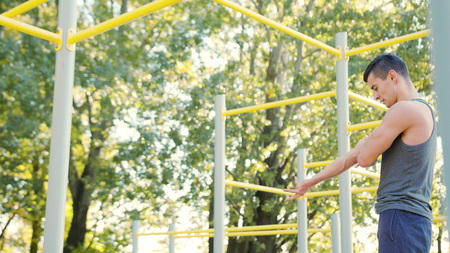 a small athlete resting after exercise Pull-up strength training exercise. Slim athlete a very fit...