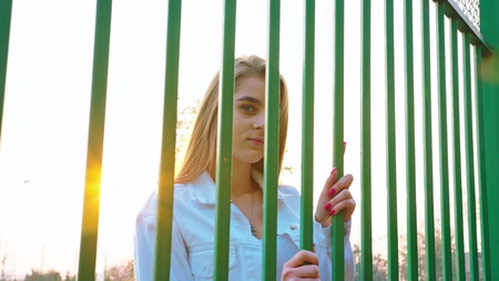 Beautiful young girl looking through the gridの写真素材