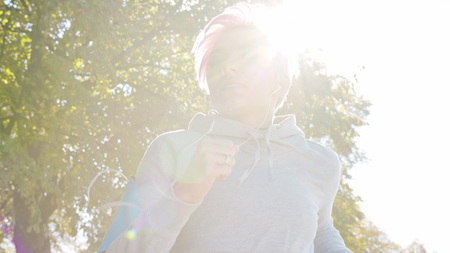 A young y with pink hair jogging in the suburbs. Glitch. Close-up shot